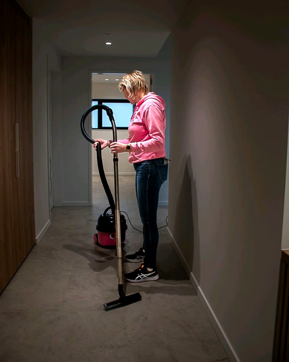 Medewerkster van Blinkuis stofzuigt de gang van een moderne woning